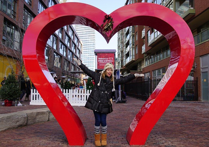 Toronto Christmas Market with a big heart display and That Backpacker Audrey Bergner in the middle with outstretched arms!