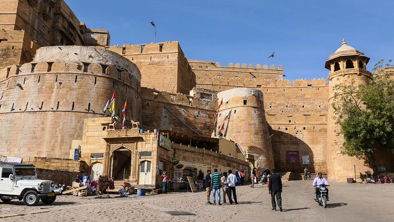 Touring Jaisalmer Fort in India with views of its imposing walls from a low vantage point in Rajasthan