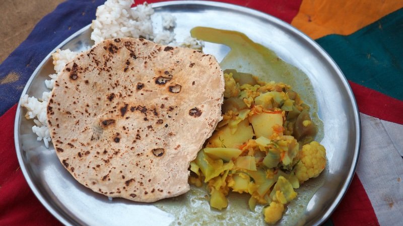 Traditional Rajasthan thali meal served in Jaisalmer, India featuring steamed rice, chapati flatbread, and mixed vegetable curry with potatoes, cauliflower, and lentils on a stainless steel plate