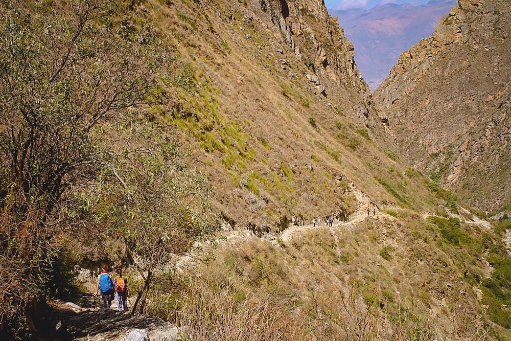 Trail on day 4 of the Santa Cruz Trek with barren landscapes and serpentine trails alongside the mountain 