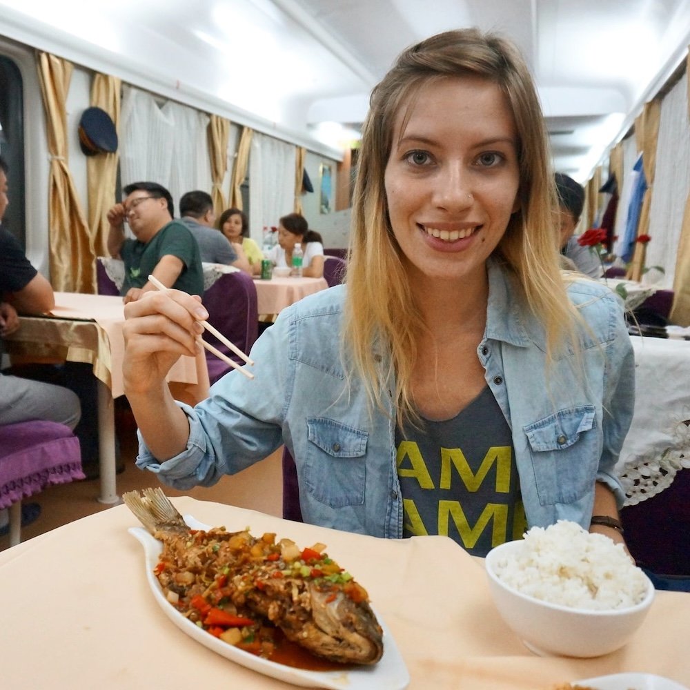 Train travel in China eating fish and rice for dinner is a hungry Audrey Bergner That Backpacker ready to chow down with chopsticks in hand