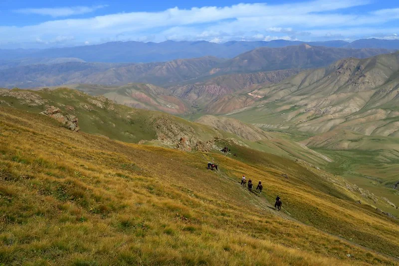 Trekking through the mountains on our way to Song Kol Lake with stunning mountain range in Kyrgyzstan 