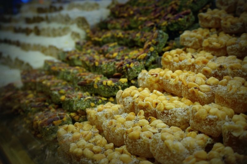 Assorted pieces of baklava and nut-filled Turkish delights on display at a sweets shop in Istanbul, Turkey, featuring layers of pistachios, hazelnuts, and powdered sugar