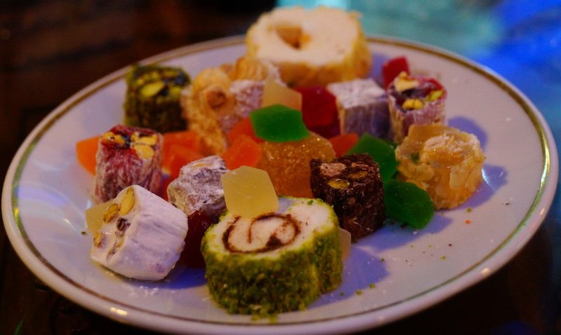 A colorful assortment of Turkish delight topped with pistachios, hazelnuts, and coconut, beautifully arranged on a plate at a café in Istanbul, Turkey