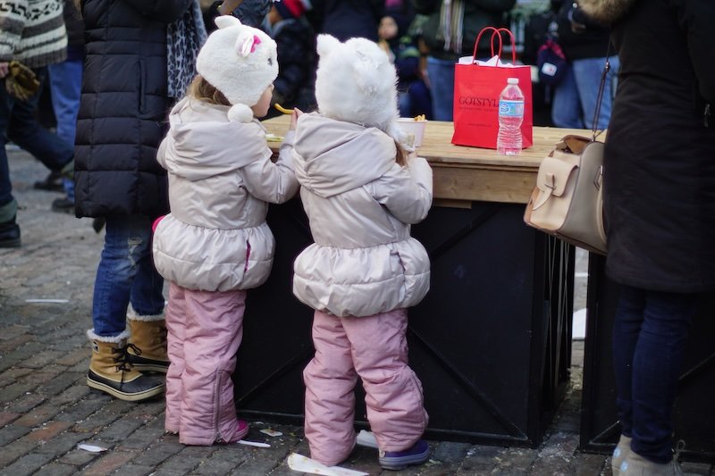 Twins eating french fries at the Toronto Christmas Market dressed in the same outfit looking so cute 