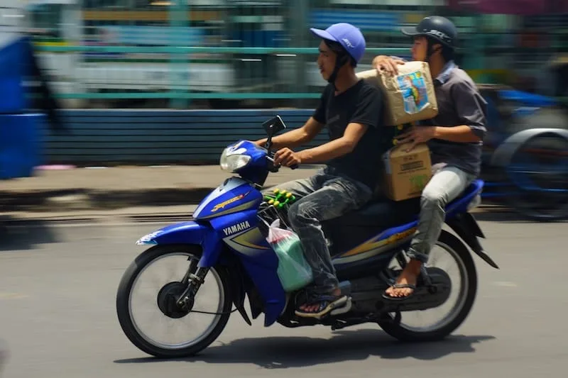 Two Vietnamese men and lots of items on one scooter in Vietnam 