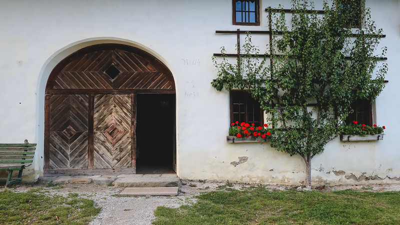 Tyrolean architecture featuring rounded doorway and trees facing the facade of the building in Tirol, Austria 