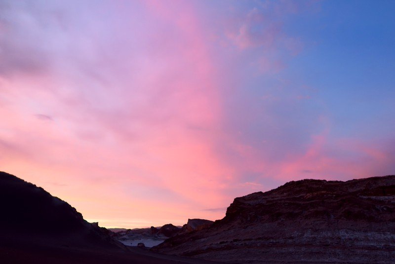 Colorful pink and purple skies at sunset over the dramatic rock formations of Valle de la Luna in Chile’s Atacama Desert.