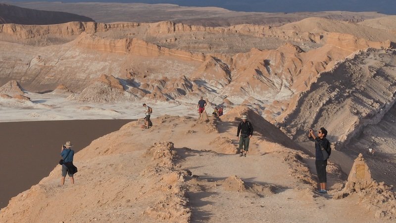 Travelers photographing the dramatic desert landscapes of Valle de la Luna during a sunset tour in Chile’s Atacama Desert Travelers photographing the dramatic desert landscapes of Valle de la Luna during a sunset tour in Chile’s Atacama Desert
