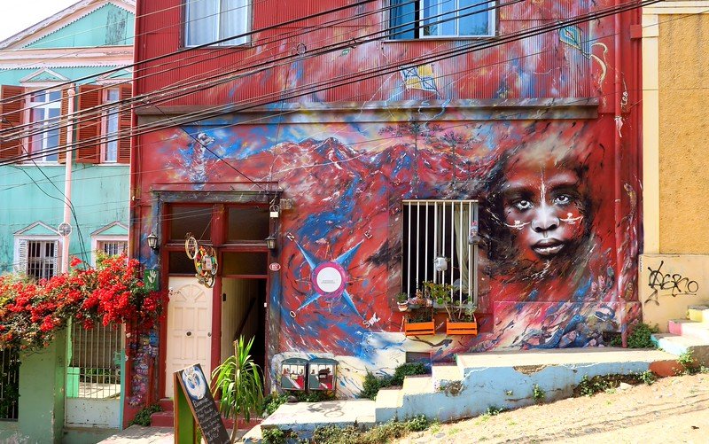 Striking street art mural of a child’s face on a red-painted building in Valparaíso, Chile, showcasing the city’s vibrant urban art and bohemian culture