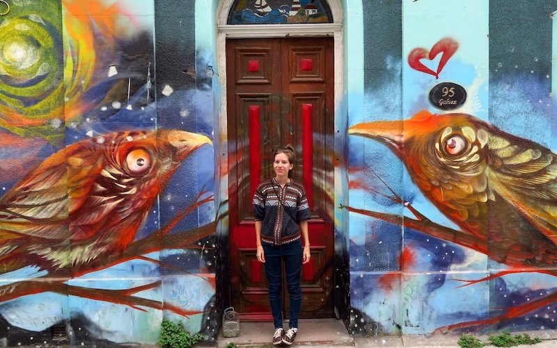 That Backpacker travel blogger Audrey Bergner posing in front of vibrant bird mural street art in Valparaíso, Chile