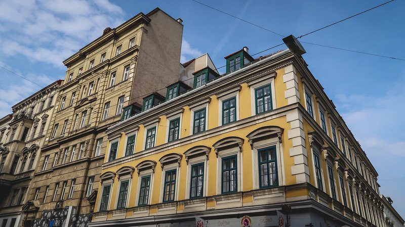 Elegant historic buildings with ornate facades and green-trimmed windows showcasing classic Vienna architecture under a bright blue sky