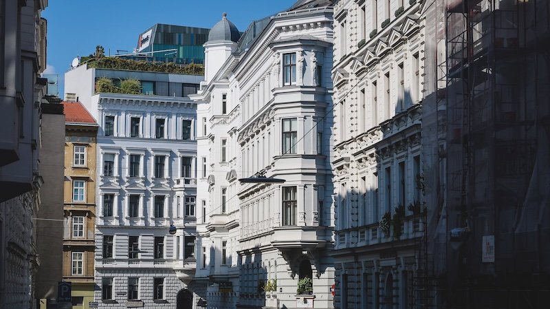 Elegant historic architecture along a quiet side street in Vienna, Austria, with ornate white facades, classical details, and soft morning shadows highlighting the buildings’ intricate design Elegant historic architecture along a quiet side street in Vienna, Austria, with ornate white facades, classical details, and soft morning shadows highlighting the buildings’ intricate design