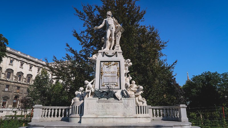 Ornate marble monument of Wolfgang Amadeus Mozart surrounded by cherub statues in Vienna, Austria, gleaming under a clear blue sky Ornate marble monument of Wolfgang Amadeus Mozart surrounded by cherub statues in Vienna, Austria, gleaming under a clear blue sky