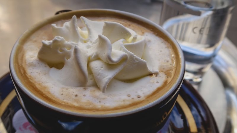 Close-up of a traditional Viennese coffee topped with a swirl of whipped cream, served alongside a glass of water at a café in Vienna, Austria Close-up of a traditional Viennese coffee topped with a swirl of whipped cream, served alongside a glass of water at a café in Vienna, Austria