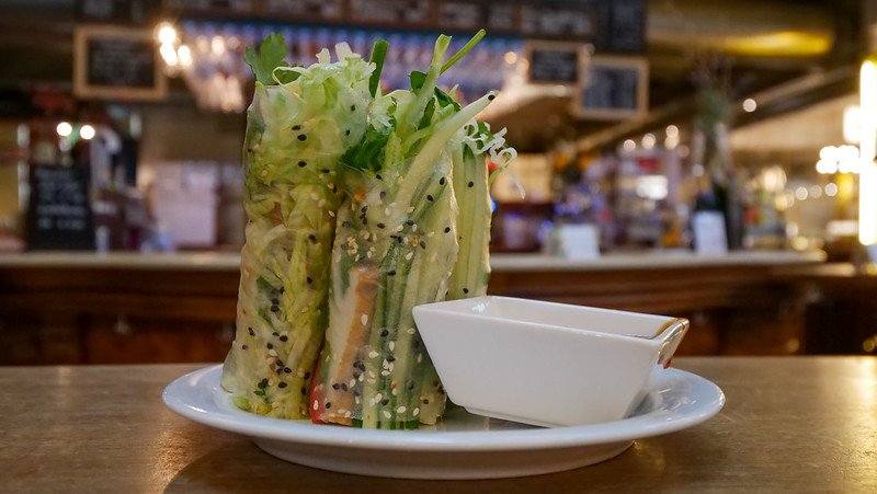 Fresh Vietnamese spring rolls filled with crisp vegetables and sprinkled with sesame seeds, served with a dipping sauce at Markthalle Freiburg in Freiburg im Breisgau, Germany