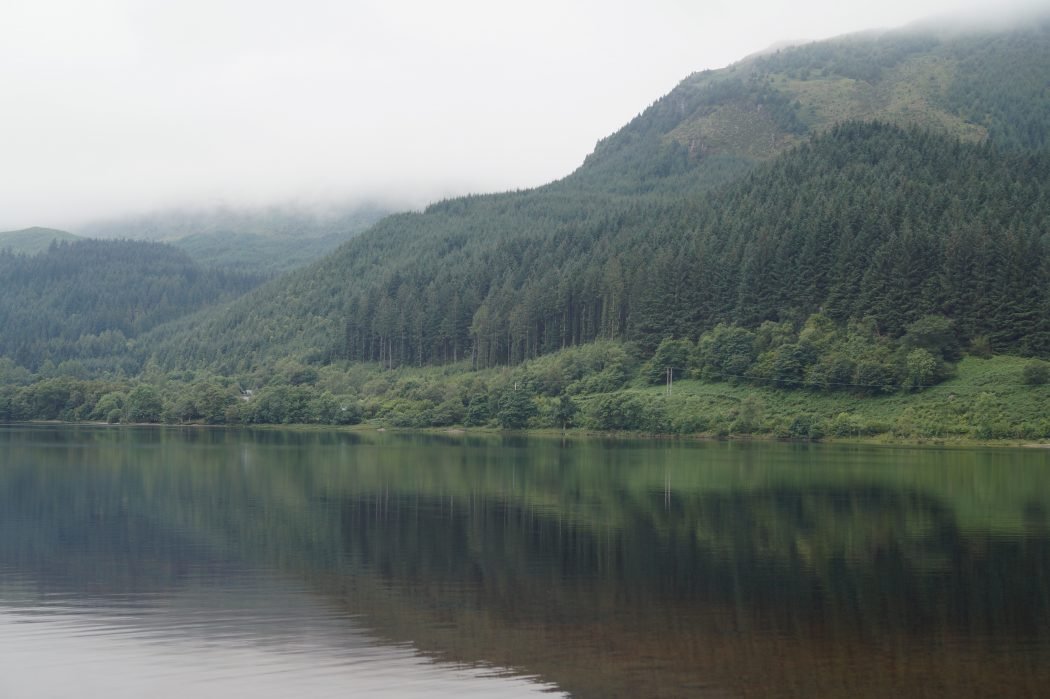 Visiting Loch Lomond & The Trossachs National Park on a weekend trip with calm waters and gorgeous greenery on display 