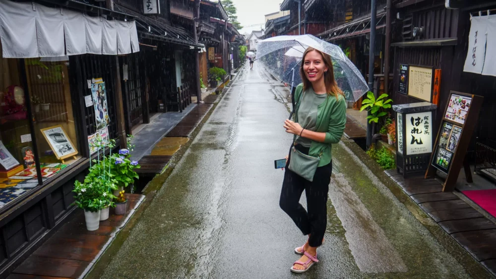Visiting Takayama, Japan and discovering some of the best things to do in the city is That Backpacker Audrey Bergner embracing the rain with an umbrella 