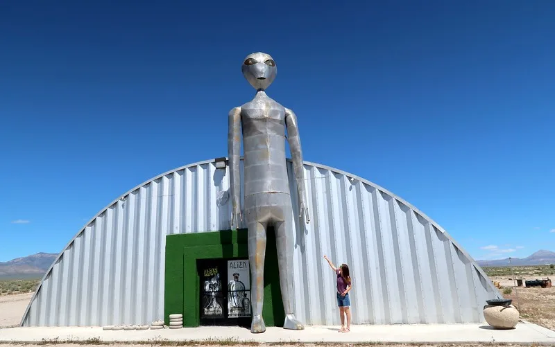 Visiting the Alien Research Center along the ET Highway with a giant alien mural and Audrey Bergner That Backpacker posing beside it for scale in Nevada