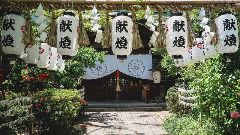 Visiting the Horikoshi Shrine on our tour of Osaka, Japan with white lanterns featuring Japanese characters at the entrance