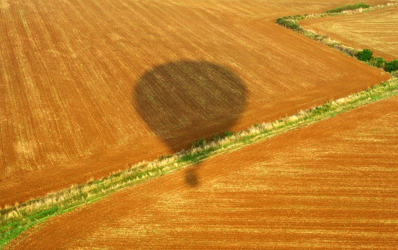 Vol de Coloms hot air balloon flight in Costa Brava with a shadow being cast over the farm field 
