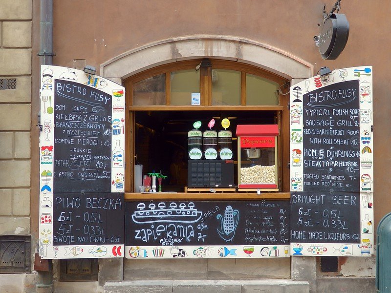 Charming snack shop in Warsaw, Poland with colorful chalkboard menus advertising pierogi, soups, zapiekanka, and draught beer. These casual bistros in the city’s Old Town are perfect for sampling traditional Polish street food and quick bites