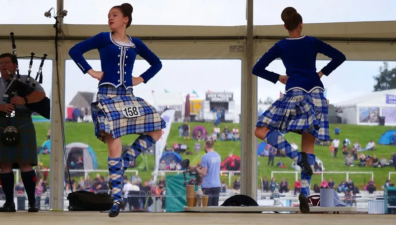 Watching the Highland Dancing competition with two competitors wearing blue outfits competing at the games 