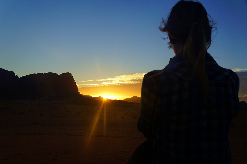 Watching the sunset in Wadi Rum, Jordan as it heads over the rock formations with a mesmerized That Backpacker Audrey Bergner taking it in