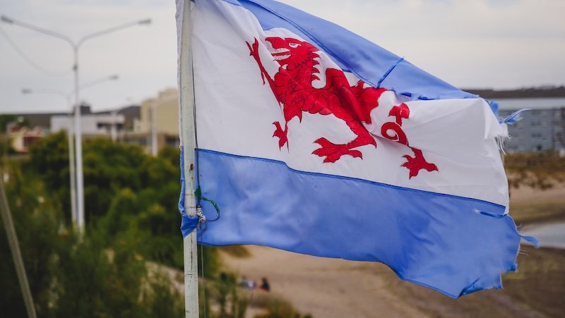 The Welsh Patagonian flag with its red dragon symbol flutters in the coastal breeze of Puerto Madryn, Argentina, representing the enduring legacy of Welsh settlers in Patagonia and the cultural ties celebrated in the region today