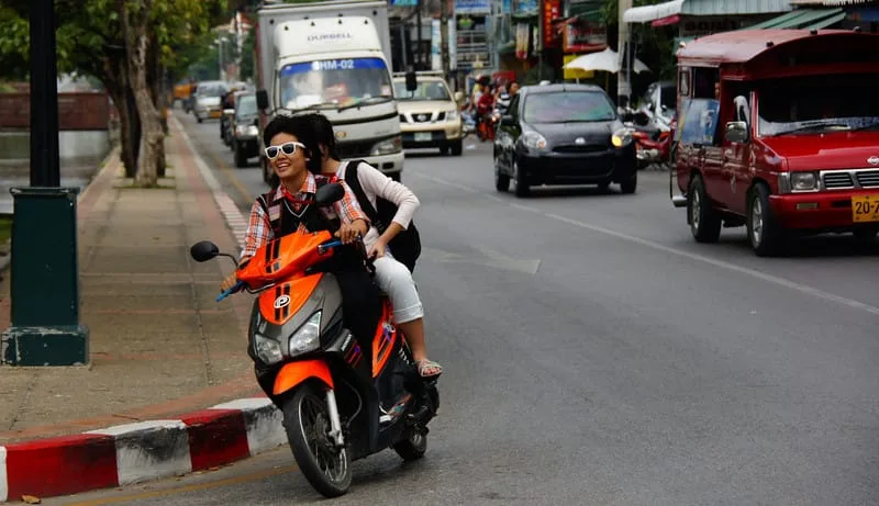 Why I am NOT Renting a Scooter or a Motorbike in Southeast Asia with locals riding on a scooter with smiles and no helmet!