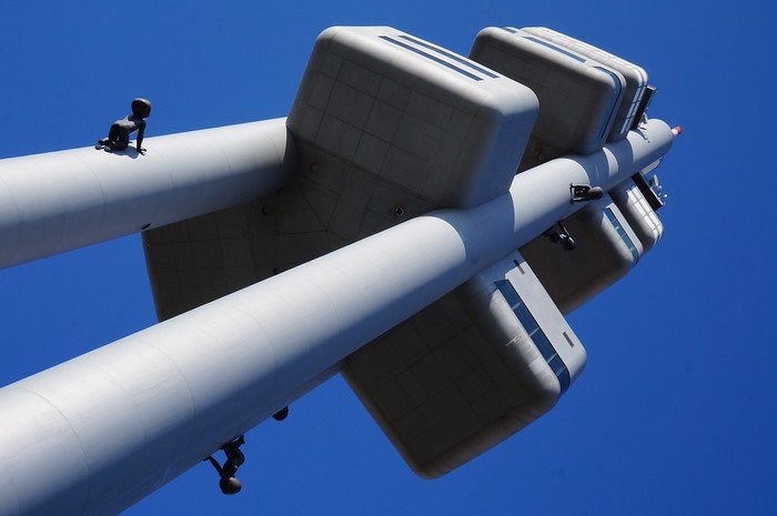 Upward view of the futuristic Žižkov Television Tower with Crawling Babies sculptures by David Černý attached to its pillars, set against a deep blue sky in Prague, Czech Republic